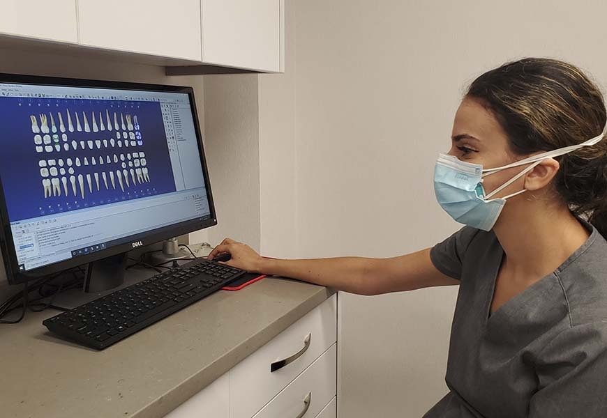 Profesional dental revisando una radiografía dental digital y un plan de tratamiento cosmético en un ordenador en una clínica dental del Bronx.